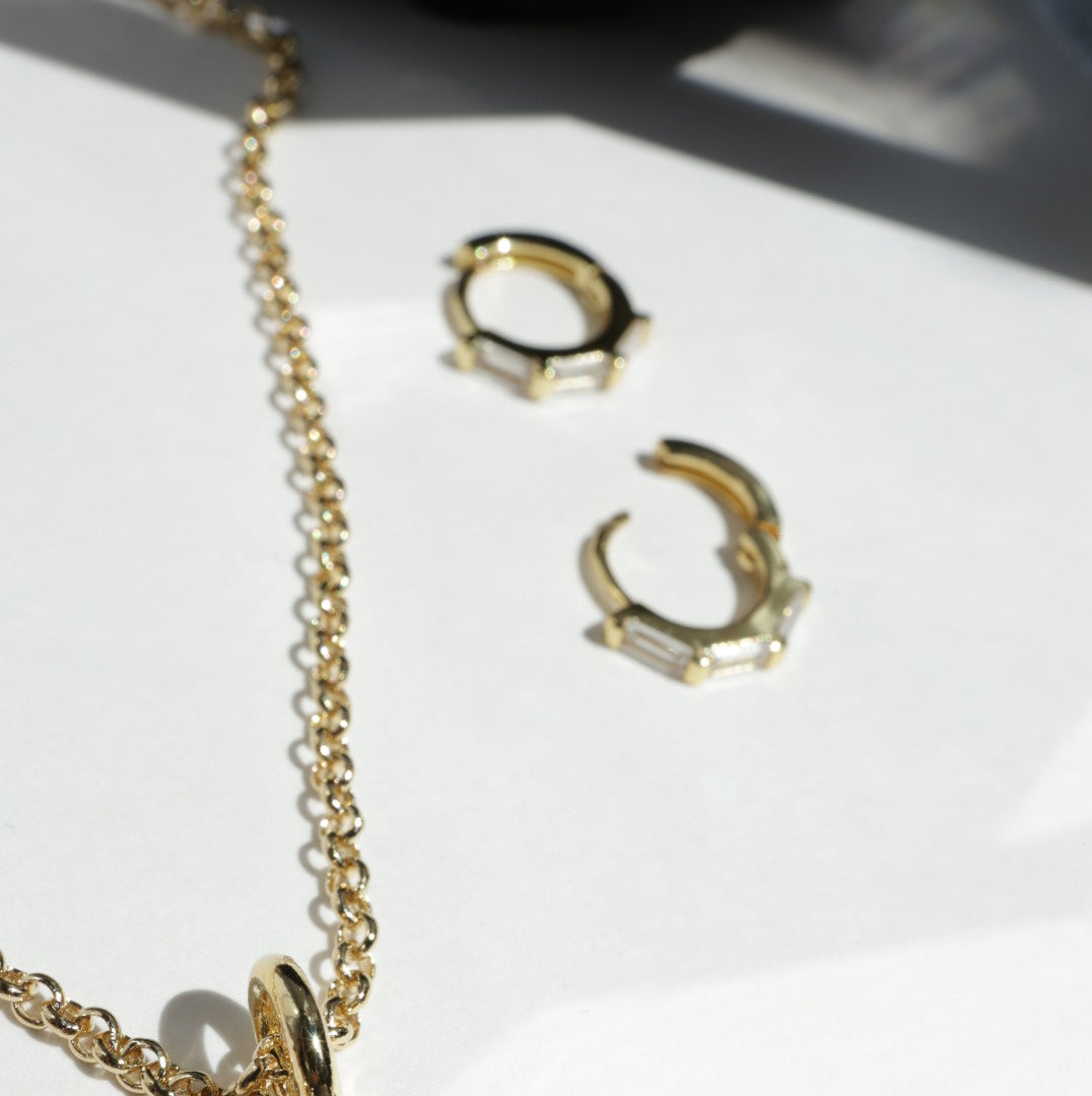 Gold jewelry set with earrings and a necklace on a white background