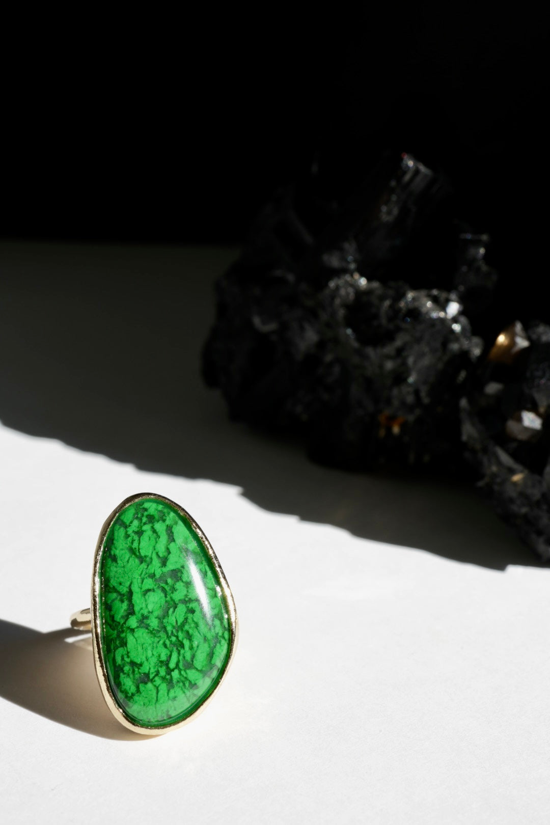 Maw Sit Sit vibrant Green stone ring with gold band on a white surface with black background