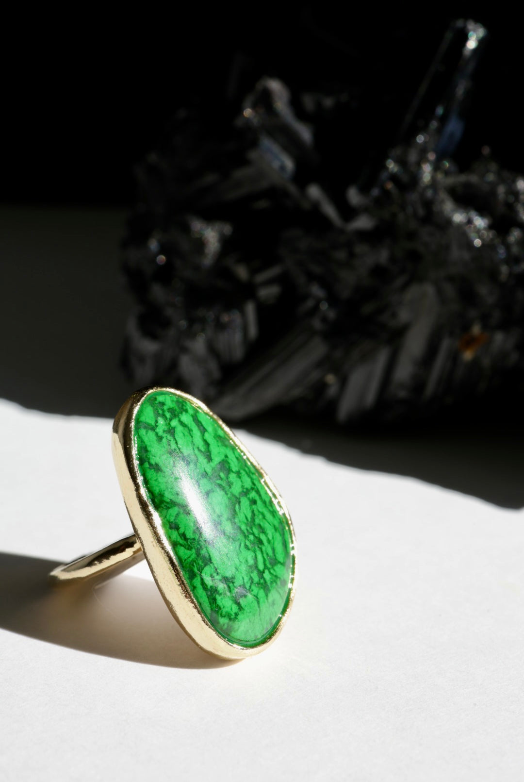 Green stone  ring with gold band on a white surface