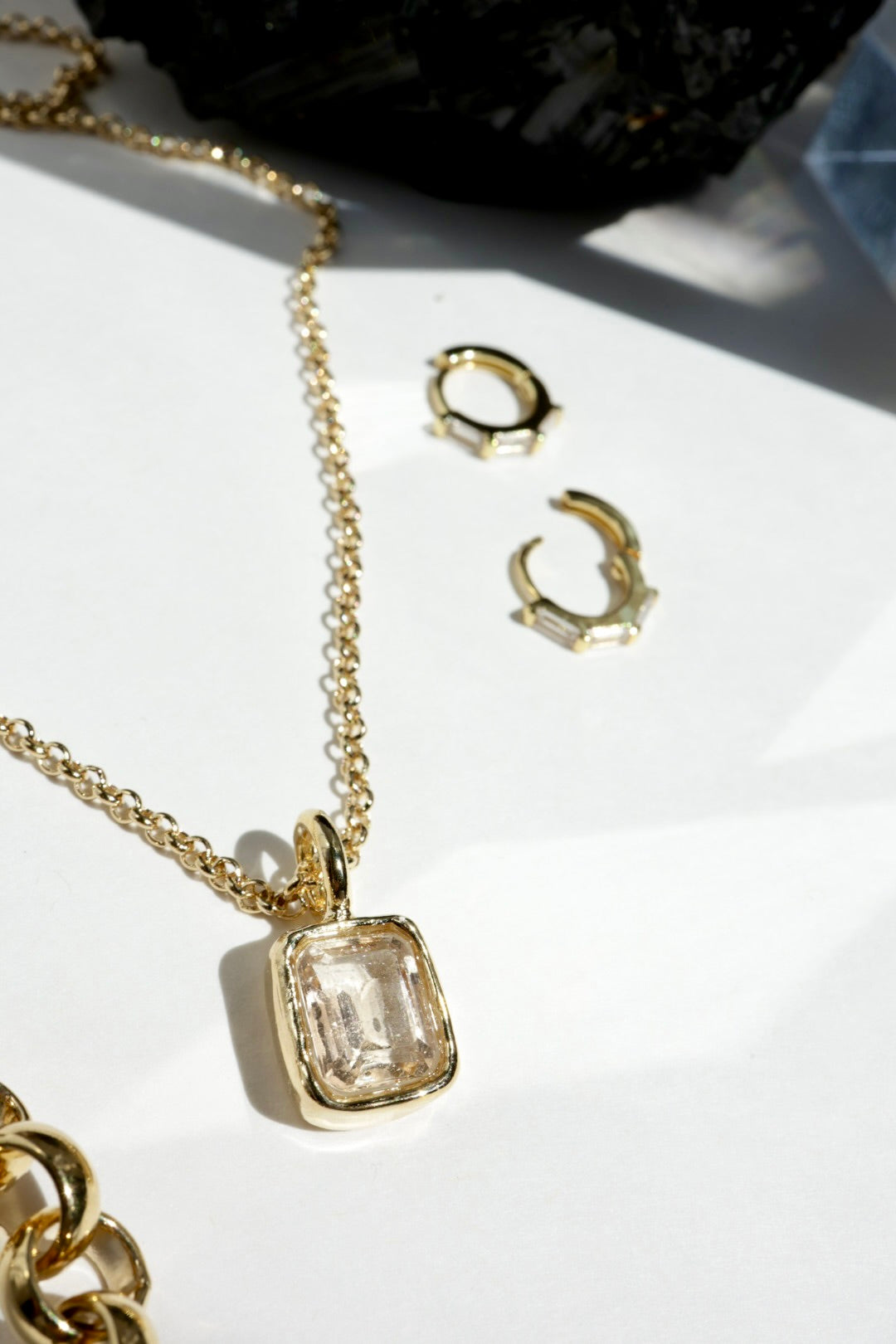 Gold necklace with pendant and earrings on a white surface