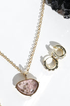 Gold necklace with a pink stone pendant on a white background